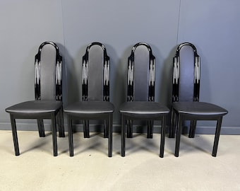 May include: Four black dining chairs with a high-backed design. The chairs have a glossy black finish with a padded, grey upholstered backrest and seat. The legs are straight and square, providing a modern aesthetic.