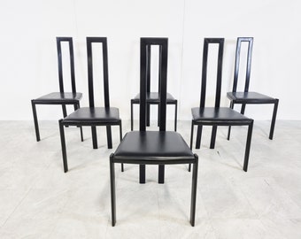 May include: Six black dining chairs with a simple, modern design. The chairs have a black leather seat and a black metal frame.