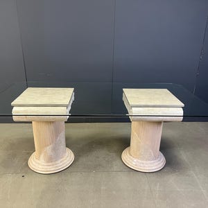Puede incluir: Mesa de comedor rectangular con tapa de cristal y dos pedestales de piedra beige. Los pedestales tienen un diseño acanalado y una base curva. La mesa es de color neutro y encajaría en un comedor moderno. La mesa mide unos 180 cm de largo.