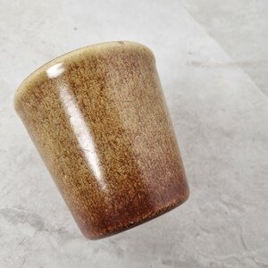 May include: A brown ceramic mug with a speckled glaze.