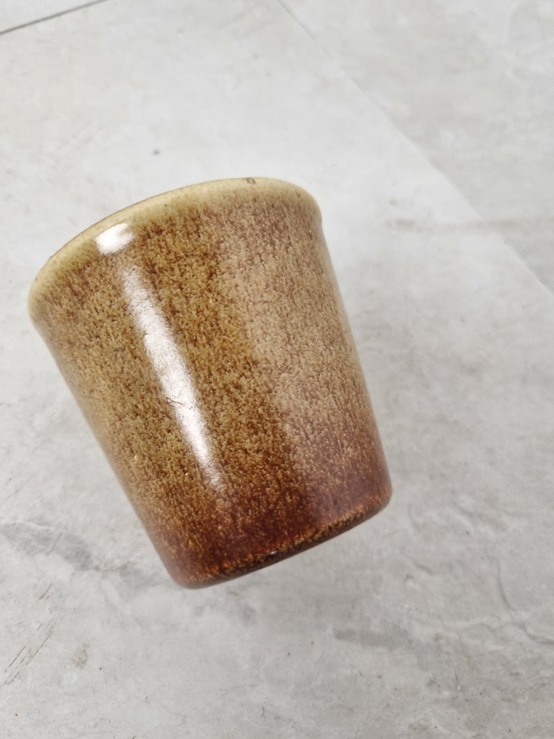 May include: A brown ceramic mug with a speckled glaze.