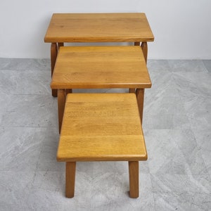 Puede incluir: Un conjunto de tres mesas nido de madera. Las mesas son de madera marr&oacute;n claro y tienen un dise&ntilde;o simple y moderno.