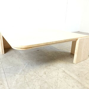 May include: A white travertine coffee table with a curved top and a rectangular base. The table is made of natural stone and has a unique, organic look.