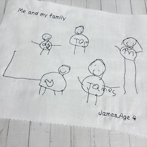 May include: A white fabric with a child's drawing of a family, featuring stick figures and the text "Me and my family." The drawing includes names and the text "James, Age 4."