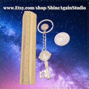 May include: A silver-colored key chain with a key-shaped pendant and a round medallion. A quarter and a small coin are attached to the key chain. A wooden ruler is next to the key chain. The Etsy shop name is visible.