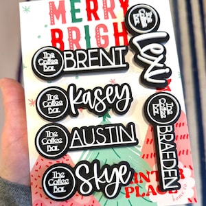 Puede incluir: Un conjunto de etiquetas con nombres en blanco y negro con el texto &laquo;MERRY BRIGHT&raquo; en una tarjeta navide&ntilde;a. Las etiquetas presentan nombres como &laquo;Brent&raquo;, &laquo;Kasey&raquo;, &laquo;Austin&raquo;, &laquo;Skye&raquo;, &laquo;Lexi&raquo; y &laquo;Braeden&raquo;. Tambi&eacute;n est&aacute; presente el logotipo de The Coffee Bar.