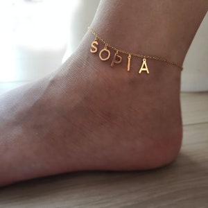 Puede incluir: Tobillera de oro con el nombre "Sophia" escrito en abalorios individuales.
