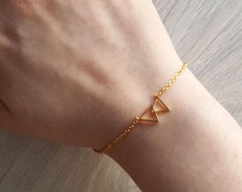 Könnte beinhalten: Ein goldenes Kettenarmband mit einem zarten Anhänger in Form eines Doppel-Dreiecks.