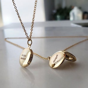 May include: Two gold locket necklaces with engraved text. One locket reads "Abigail" and the other reads "IV.XIII.MMXXIX".