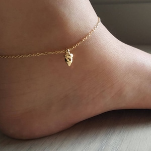May include: A gold anklet with a small heart charm. The anklet is made of a delicate chain and is perfect for layering with other jewelry.