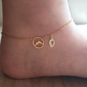 May include: Gold ankle bracelet with a mountain charm and a charm with the letter Y.