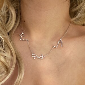 May include: A silver necklace with three constellation pendants. The constellations are Libra, Gemini, and Aquarius.