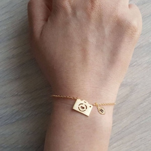 Peut inclure: Bracelet en chaîne dorée avec un charme en forme d'appareil photo et un charme en forme de lettre B.