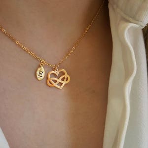 以下が含まれることがあります： 小さな無限大のハートのチャームと、葉のチャームに「E」の文字が刻まれた、金のチェーンネックレスです。