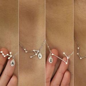 May include: Four silver necklaces with a constellation design and a small pendant with a letter on each. The constellations are different on each necklace. The pendants are all the letter A.