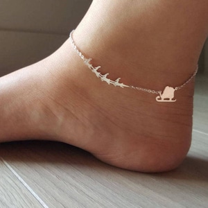 May include: Silver ankle bracelet with a delicate chain and a charm of a sleigh with people riding in it.