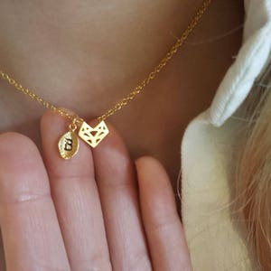 以下が含まれることがあります： 小さな幾何学的なペンダントと「E」の文字のチャームがついたゴールドチェーンネックレス