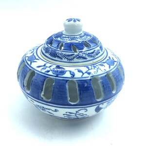 May include: A blue and white porcelain incense burner with a lid. The burner has a floral design and is decorated with blue and white paint. The lid has a small hole in the center.