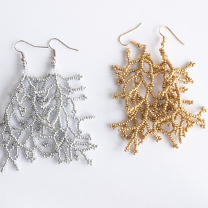 May include: A pair of long, beaded earrings. One pair is silver and the other is gold. The earrings are shaped like branches.