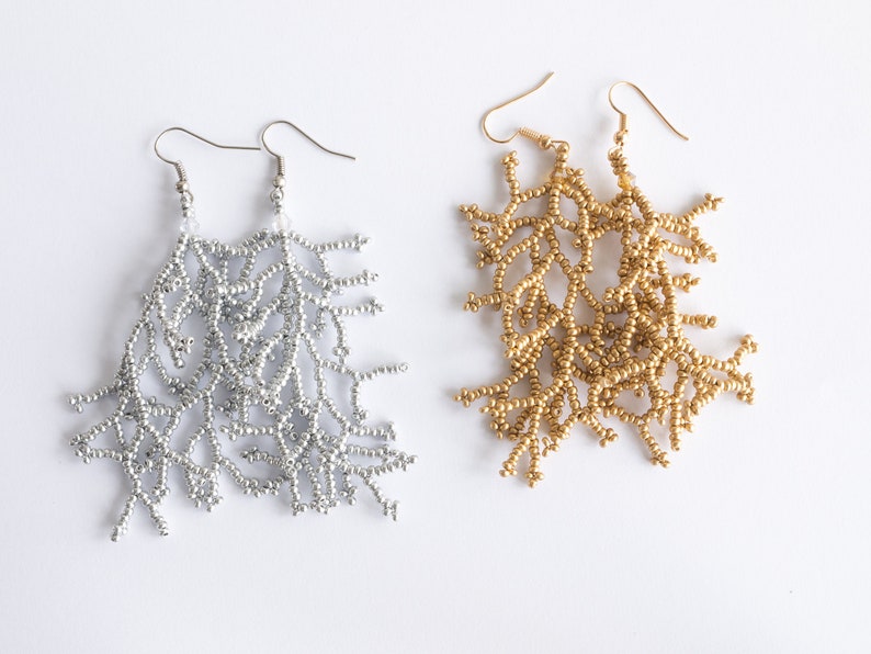 May include: A pair of long, beaded earrings. One pair is silver and the other is gold. The earrings are shaped like branches.