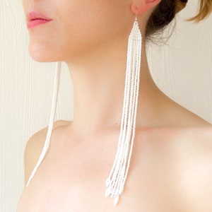 Può includere: Orecchini lunghi con perline bianche. Gli orecchini sono realizzati con piccole perline bianche infilate insieme per creare un look lungo, sottile e delicato.