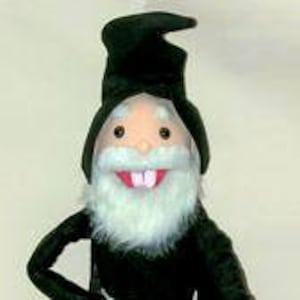May include: A black felt puppet with a white beard and a pointed hat. The puppet has a large, toothy grin.