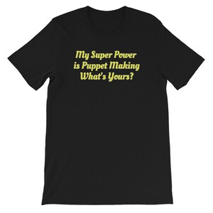 Puede incluir: Camiseta negra con texto amarillo que dice "My Super Power is Puppet Making What's Yours?"