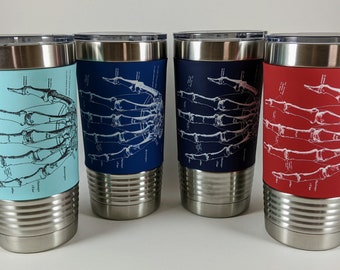 May include: Four stainless steel insulated tumblers with lids. Each tumbler has a different coloured sleeve: light blue, navy, navy, and red. Each sleeve features a white illustration of a hand skeleton.