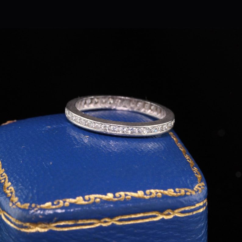 May include: A silver band ring with a row of small diamonds set in the band.