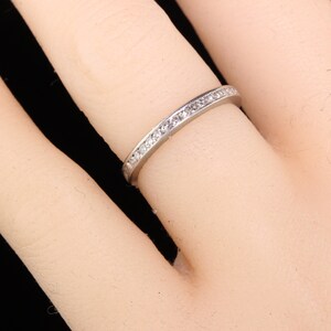 May include: A thin silver band with a row of small diamonds set in a channel setting.