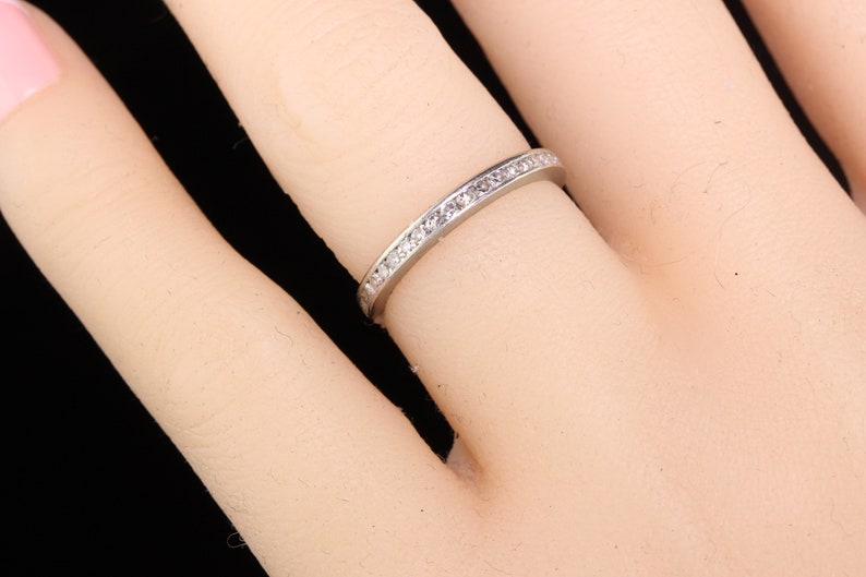 May include: A thin silver band with a row of small diamonds set in a channel setting.