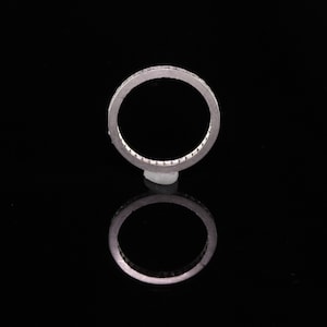 May include: A silver band ring with a row of small diamonds set in a channel setting.