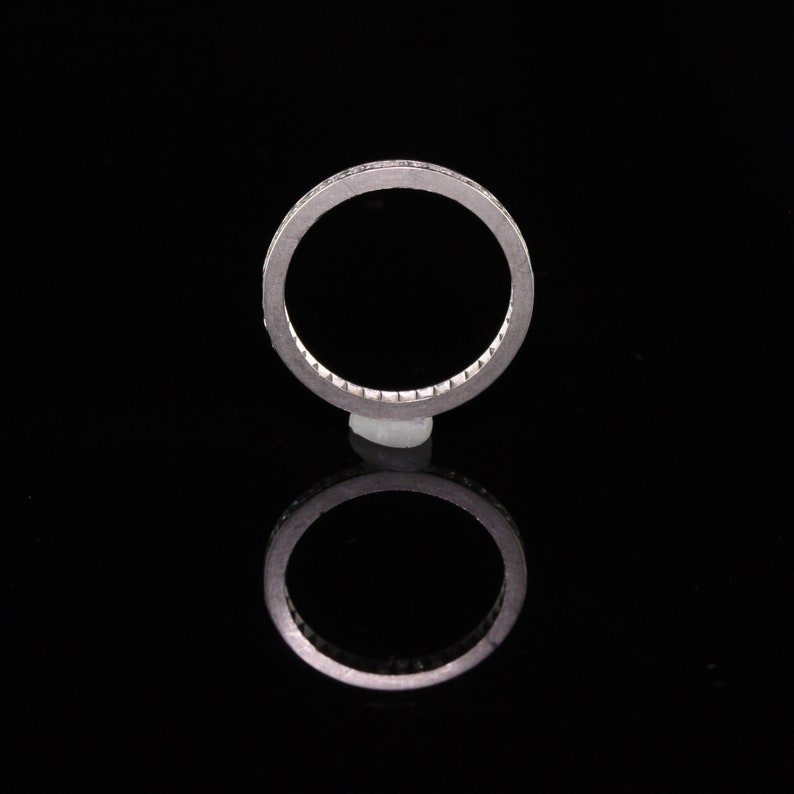 May include: A silver band ring with a row of small diamonds set in a channel setting.