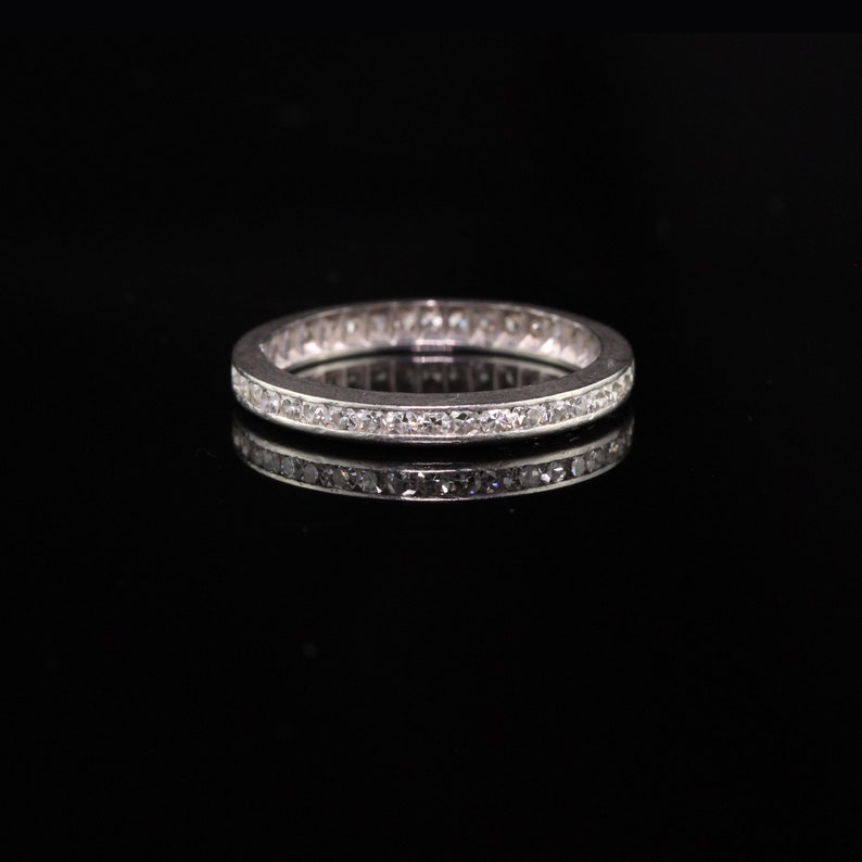 May include: A silver band ring with a row of small diamonds set in a channel setting.