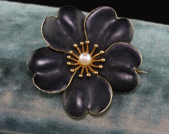 以下が含まれることがあります： 金色のセンターと真珠のアクセントが付いた黒いエナメルの花のブローチ
