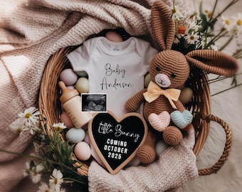 Puede incluir: Un body blanco con el texto "Baby Anderson" en él, un conejito de crochet marrón, un letrero de tiza en forma de corazón que dice "Little Bunny Coming October 2025", y una pequeña imagen de ultrasonido en una cesta de mimbre con huevos de colores pastel.