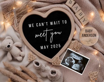 May include: A heart-shaped chalkboard sign with the text "We can't wait to meet you May 2025".  The sign is surrounded by a blanket, wooden blocks spelling "BABY", a teddy bear, and a sonogram image.