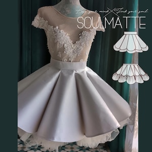 May include: A short dress featuring a nude-colored bodice with white floral lace appliqués and short sleeves. The skirt is a solid, light-colored satin with deep pleats and a tulle hem. The text SOULMATTE is visible in the upper right corner.