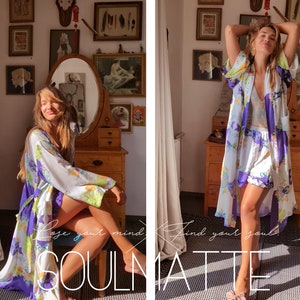 May include: A woman wearing a white and purple floral robe with a white lace bralette underneath. The robe has a long, flowing design and features a floral pattern in shades of purple, white, and green. The woman is standing in a room with a vintage aesthetic, and the text "Love your mind, find your soul, SOULMATE" is visible in the foreground.