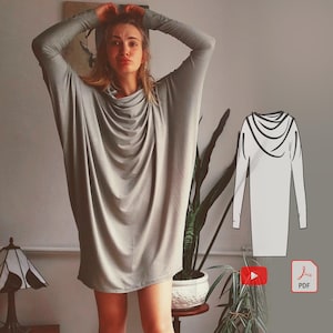 Peut inclure: Une robe tunique grise à col montant et manches longues. Un dessin au trait de la robe est présenté à droite de l'image.