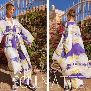 May include: A white and purple floral print kimono robe with long sleeves and a tie belt. The robe is worn over matching pants.