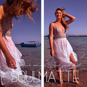 K&ouml;nnte beinhalten: Eine Frau tr&auml;gt einen wei&szlig;en Spitzenrock mit Punkten und ein graues Spitzenoberteil. Der Rock weht im Wind und die Frau steht an einem Strand mit einem blauen Boot im Hintergrund. Der Text "Love your mind. Find your soul. SOULMATE" ist auf dem Bild zu sehen.