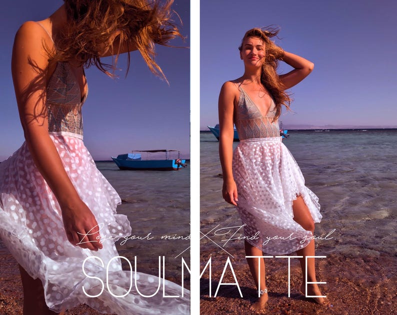 K&ouml;nnte beinhalten: Eine Frau tr&auml;gt einen wei&szlig;en Spitzenrock mit Punkten und ein graues Spitzenoberteil. Der Rock weht im Wind und die Frau steht an einem Strand mit einem blauen Boot im Hintergrund. Der Text "Love your mind. Find your soul. SOULMATE" ist auf dem Bild zu sehen.