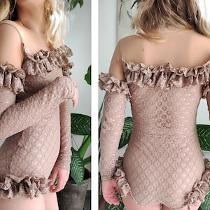 May include: A brown lace bodysuit with a sheer mesh panel at the neckline and ruffled trim around the neckline, shoulders, and hem.