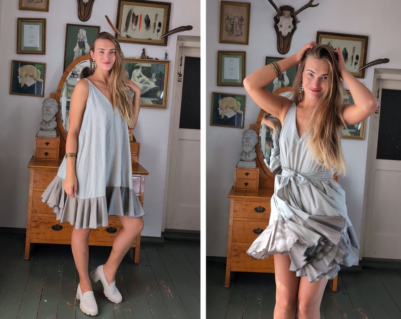 May include: A light blue dress with a V-neck and a layered, ruffled hem. The dress has a flowing, relaxed fit and is paired with white loafers. The dress is made of a soft, lightweight fabric, perfect for warm weather.