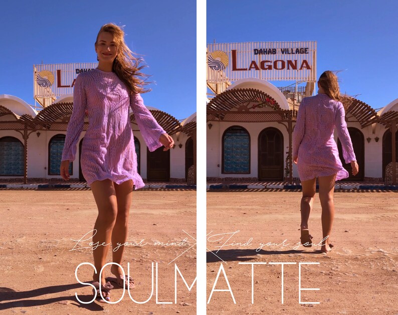 May include: A woman in a purple dress walks towards the camera in front of a building with a sign that reads "Dahab Village Lagona".