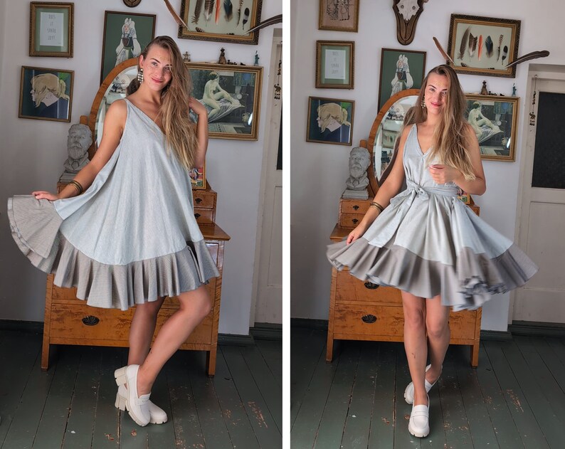May include: A light blue and gray dress with a V-neck and a layered, ruffled skirt. The dress has a flowing silhouette and is paired with white shoes. The dress is made of a soft, lightweight fabric, perfect for warm weather.