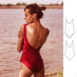 May include: A red one-piece swimsuit with a low back and a scoop neck. The swimsuit is shown on a model standing on a beach.