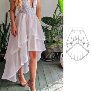 May include: A white layered tulle skirt with a high-low hemline. The skirt is asymmetrical, with a longer back and a shorter front. The skirt is made of a soft, flowing fabric.