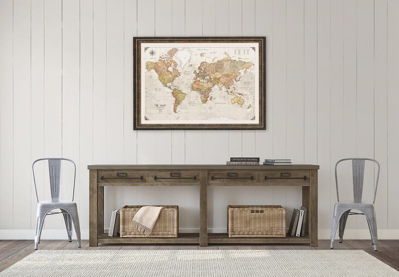 a wooden console table with two metal chairs, a framed world map hanging on the wall above the table, and two wicker baskets on the floor.